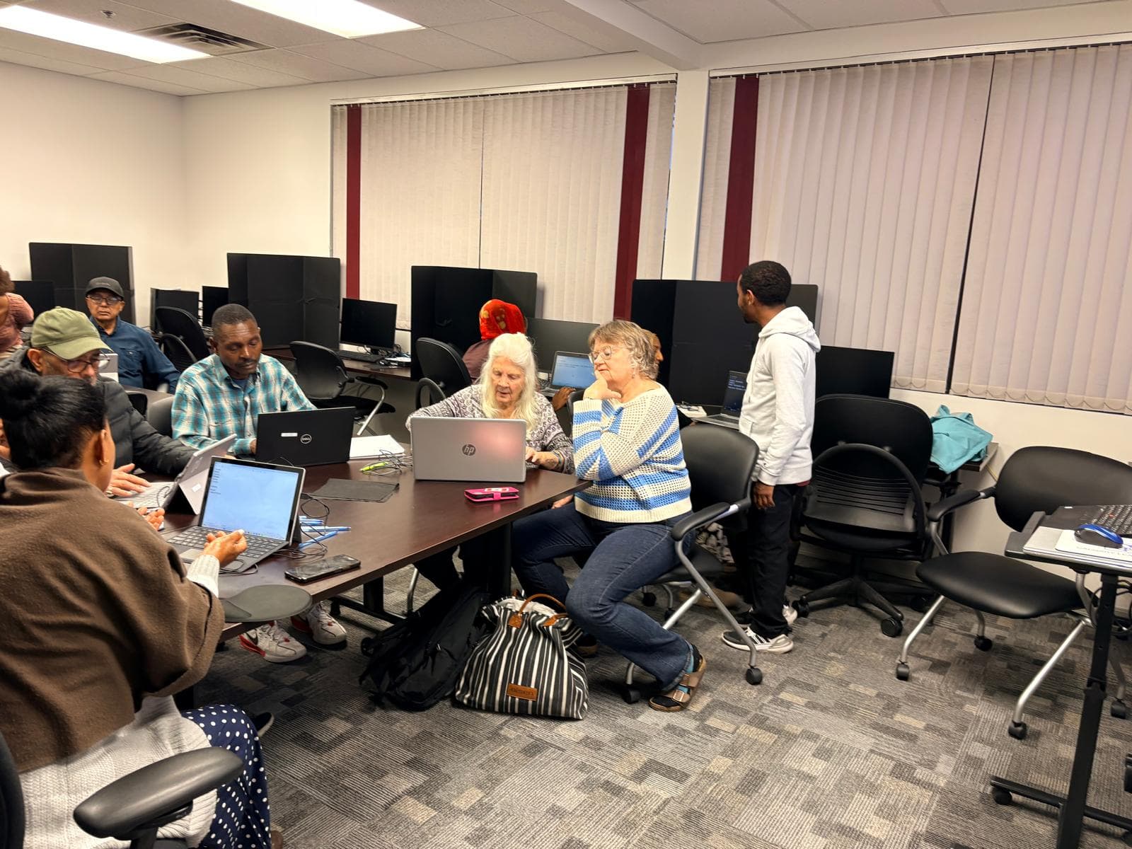 Seniors learning on laptops with a patient instructor in a computer class