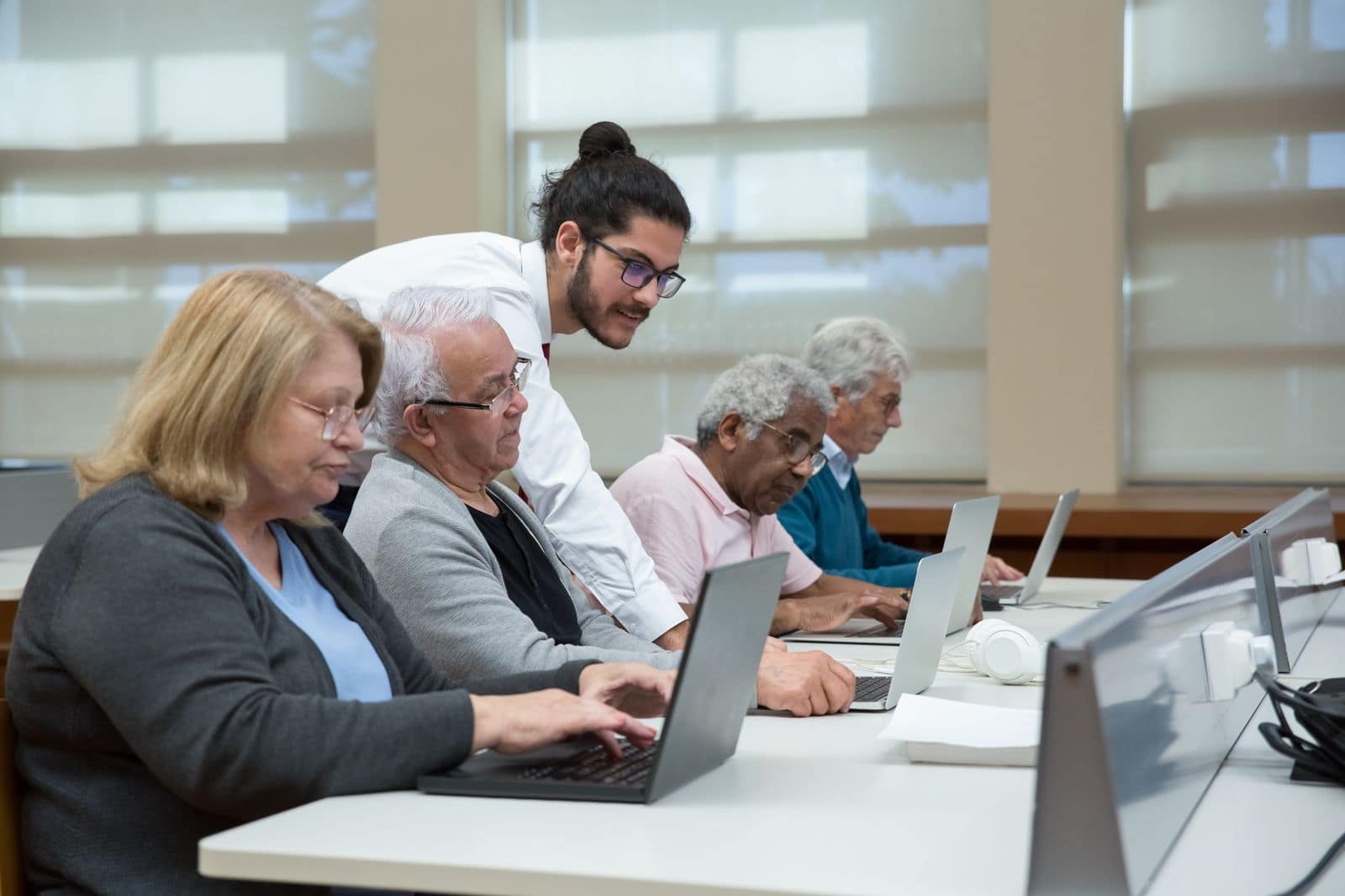 Seniors learning on laptops with a patient instructor in a computer class